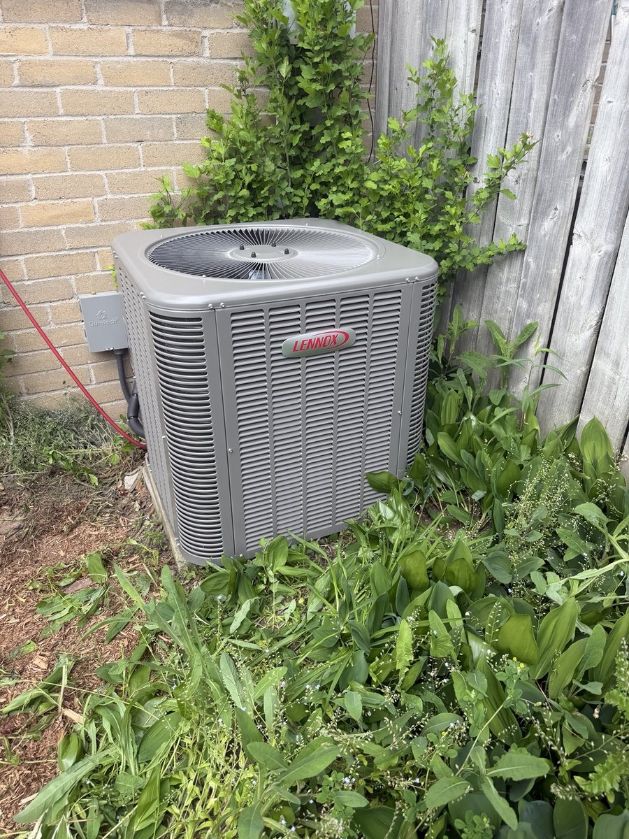 Lennox outdoor air conditioner installation beside fence and brick wall
